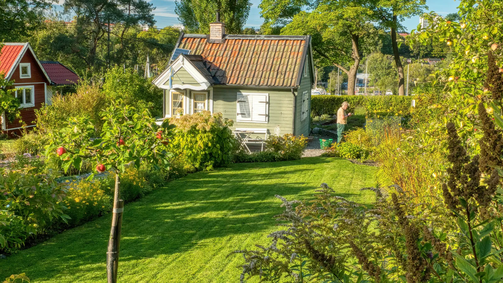 Garden path and lawn leading to a small house with a red roof