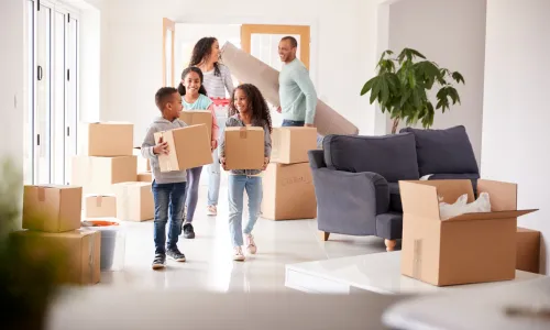 Family carrying moving boxes into a new home